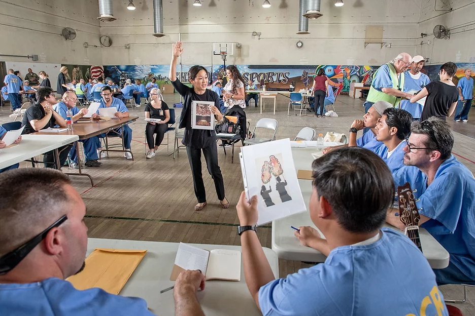 Women leading instruction with individuals at a table around her