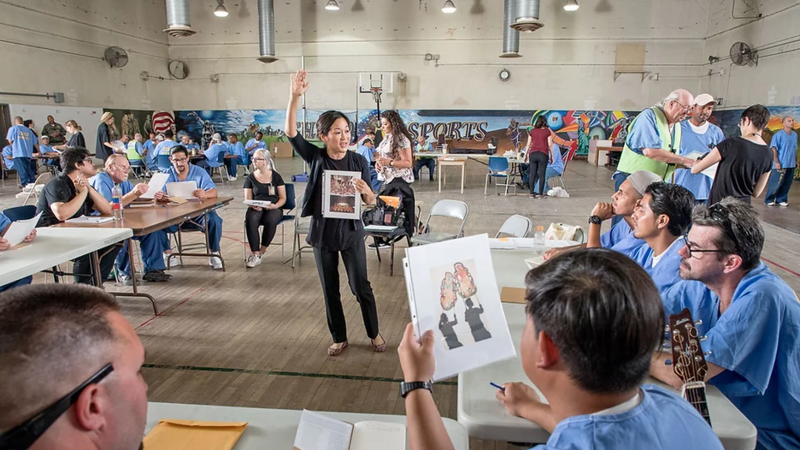 Women leading instruction with individuals at a table around her