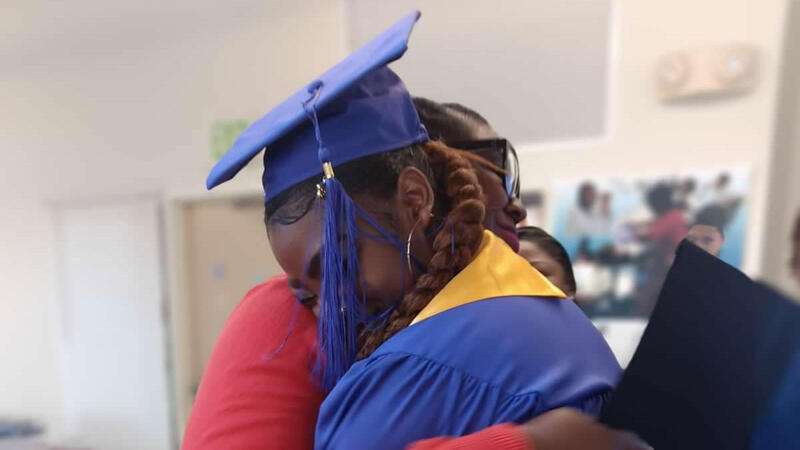 Picture of a graduating woman hugging another woman