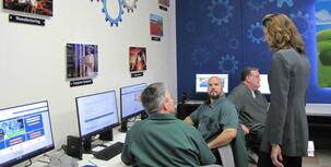 Men sitting at computers talking with a woman